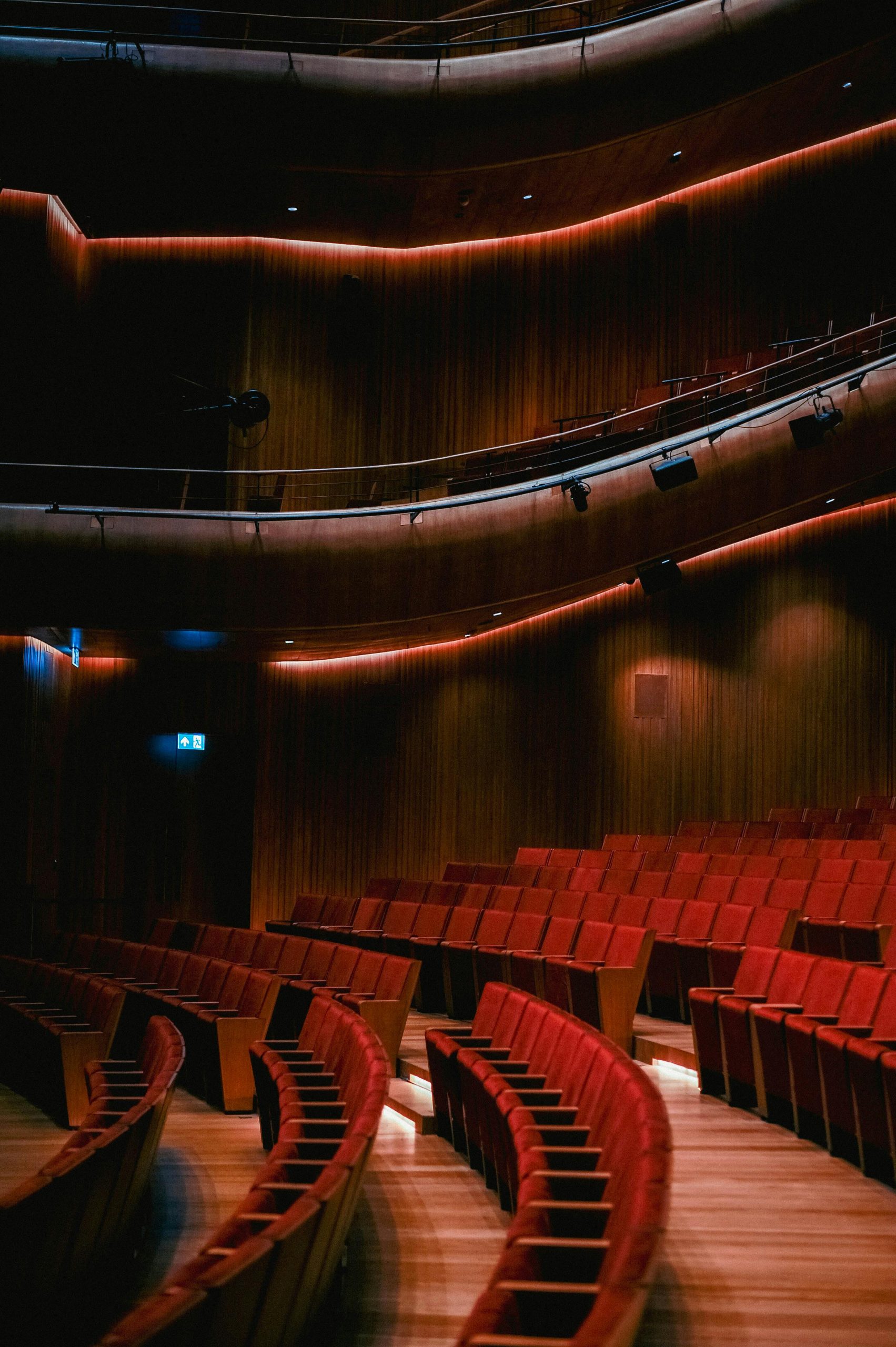 Rows of red seats in an empty auditorium with dramatic lighting.